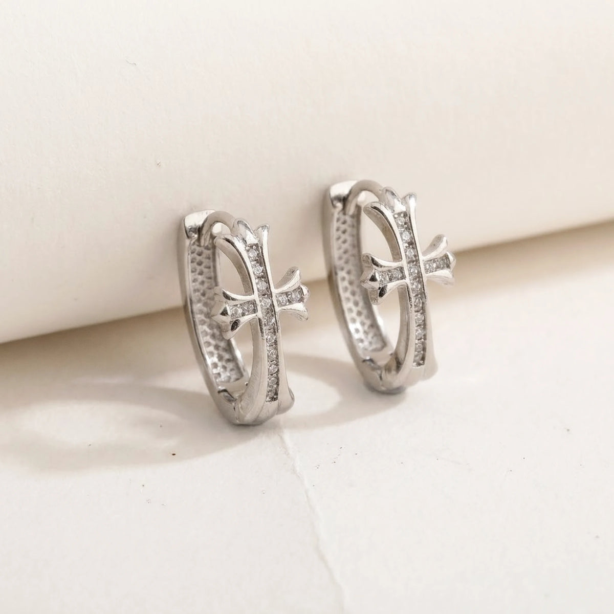 Silver tone stainless steel pave cross huggie hoop earrings, product shot on white | SKU: AUR-CRXHUG-S