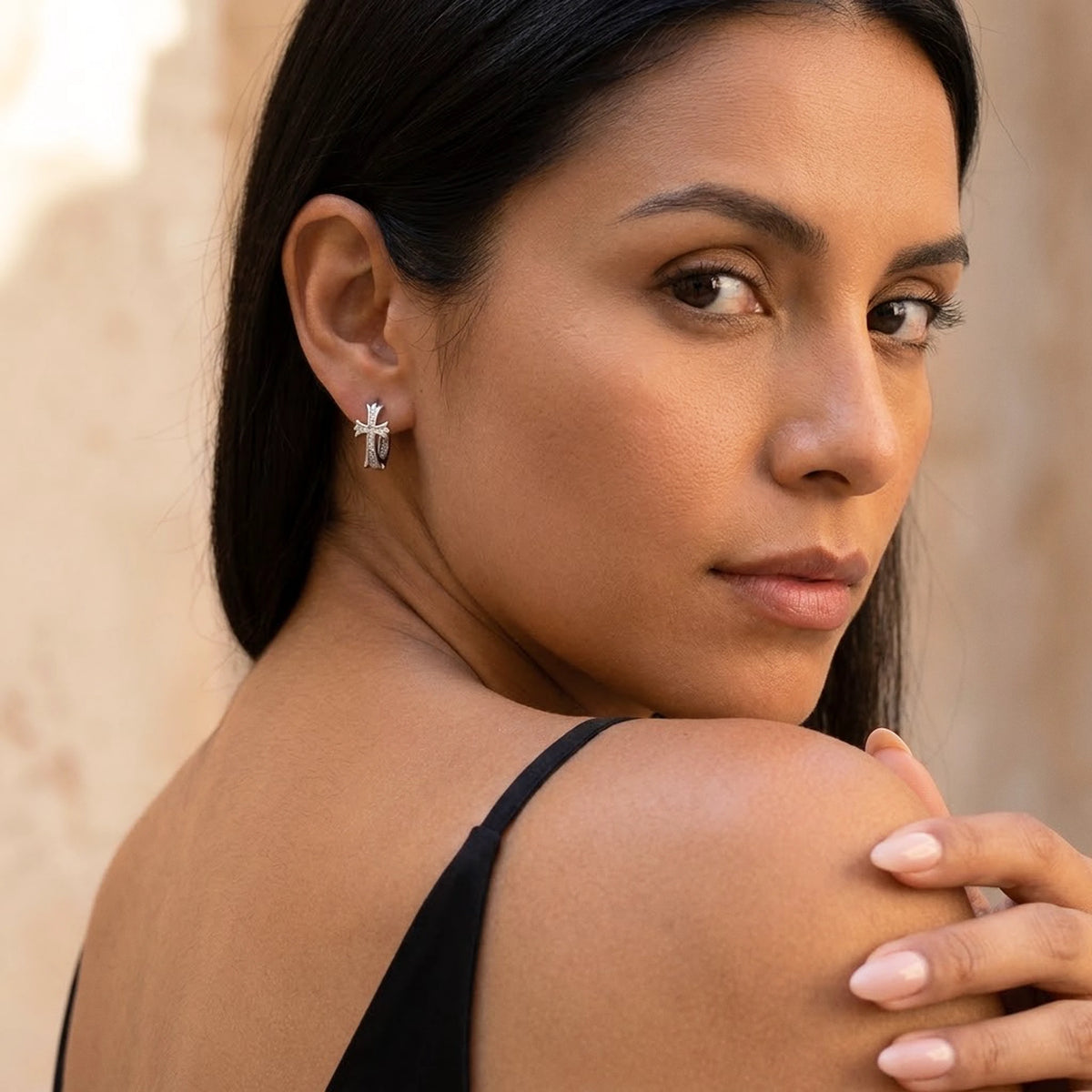 Silver tone stainless steel pave cross huggie hoop earrings, worn, over the shoulder portrait | SKU: AUR-CRXHUG-S