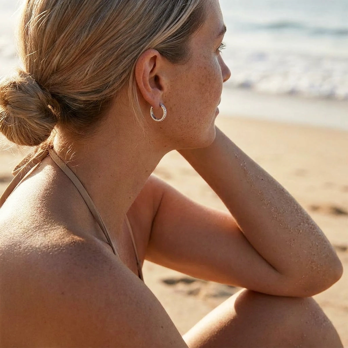 Silver tone stainless steel pave huggie hoop earrings, worn on the beach | SKU: AUR-PVHUGG-S