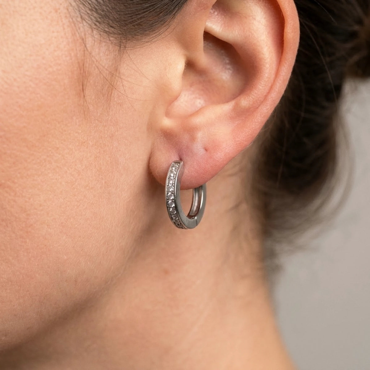 Silver tone stainless steel pave huggie hoop earrings, macro detail on the earlobe | SKU: AUR-PVHUGG-S