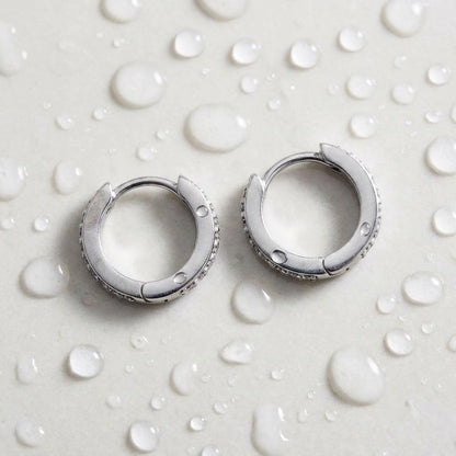 Silver tone stainless steel pave huggie hoop earrings, still life on a wet surface, waterproof | SKU: AUR-PVHUGG-S