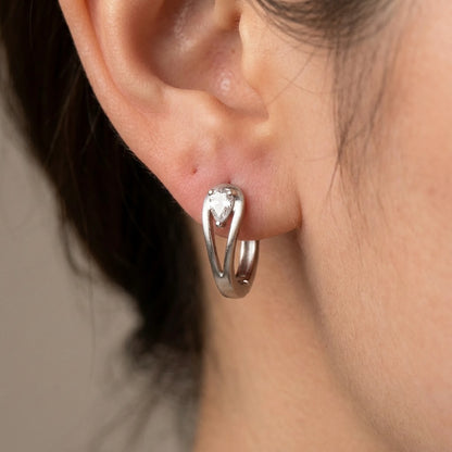 Silver tone stainless steel pear cut crystal huggie hoop earrings, macro detail on the earlobe | SKU: AUR-PRCZHG-S