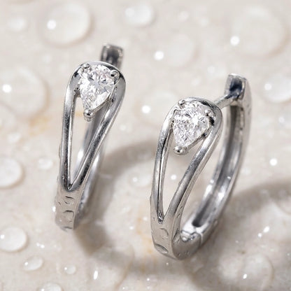 Silver tone stainless steel pear cut crystal huggie hoop earrings, still life on a wet surface, waterproof | SKU: AUR-PRCZHG-S