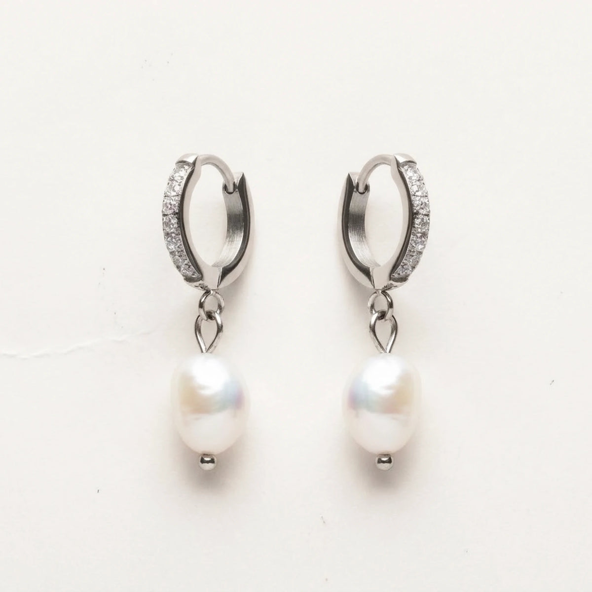 Silver tone stainless steel freshwater pearl drop huggie earrings, product shot on white | SKU: AUR-PRLHUG-S