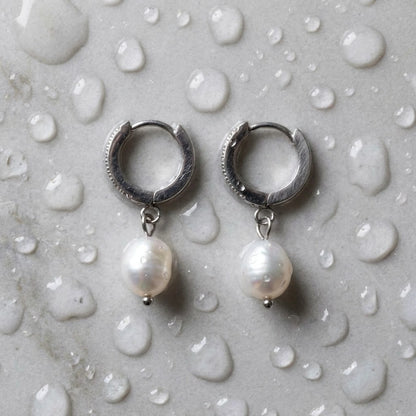 Silver tone stainless steel freshwater pearl drop huggie earrings, still life on a wet surface, waterproof | SKU: AUR-PRLHUG-S