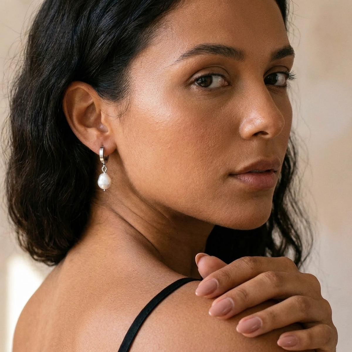 Silver tone stainless steel freshwater pearl drop huggie earrings, worn, over the shoulder portrait | SKU: AUR-PRLHUG-S