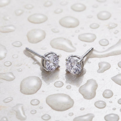 Silver tone stainless steel cubic zirconia solitaire stud earrings, still life on a wet surface, waterproof | SKU: AUR-SOLSTD-S