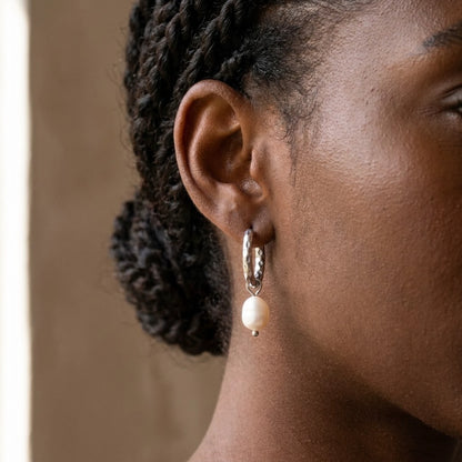 Silver tone stainless steel twisted rope pearl drop hoop earrings, worn close up on the ear