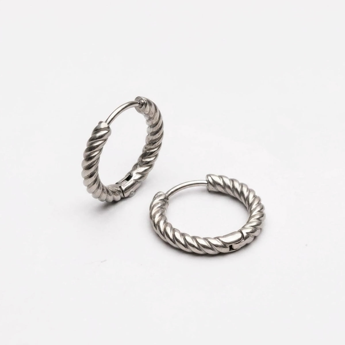 Silver tone stainless steel twisted rope huggie hoop earrings, product shot on white | SKU: AUR-TWRHUG-S