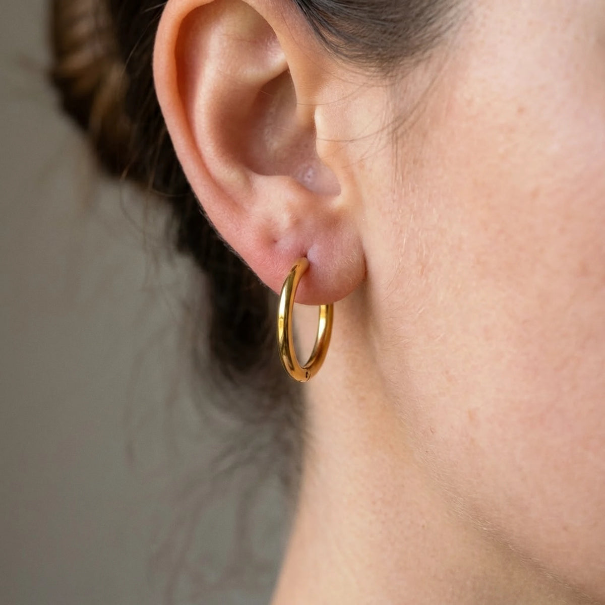 Silver tone stainless steel waterproof hoop earrings, macro detail on the earlobe | SKU: AUR-CLSHOP-S