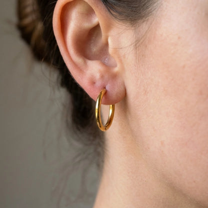 Silver tone stainless steel waterproof hoop earrings, macro detail on the earlobe | SKU: AUR-CLSHOP-S