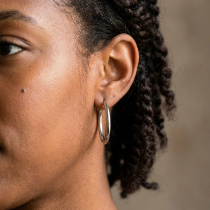 Silver tone stainless steel waterproof hoop earrings, worn close up on the ear
