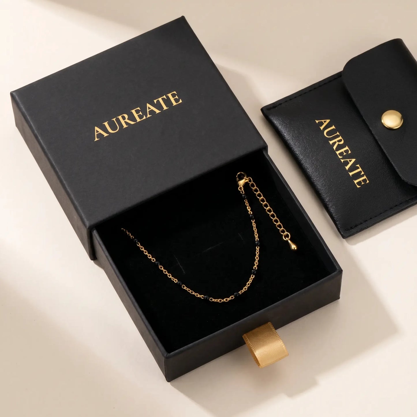 AUREATE matte black gift box with slide drawer and leather pouch, gold foil logo, black bead anklet inside