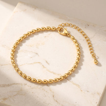 Gold oval bead anklet packshot on travertine