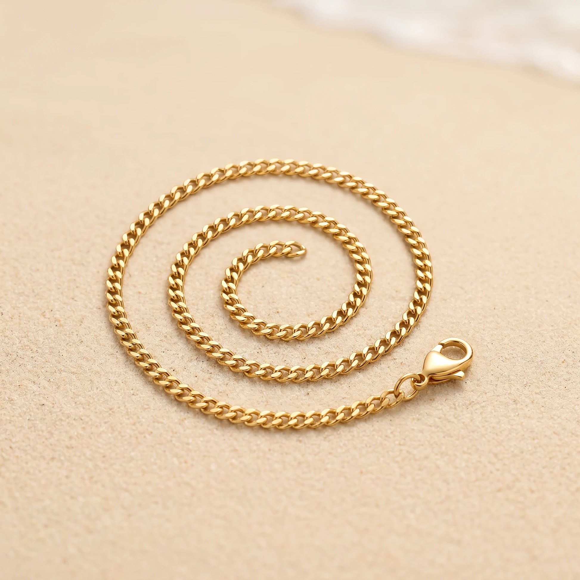 18k gold 4mm curb-link anklet coiled packshot on warm sand