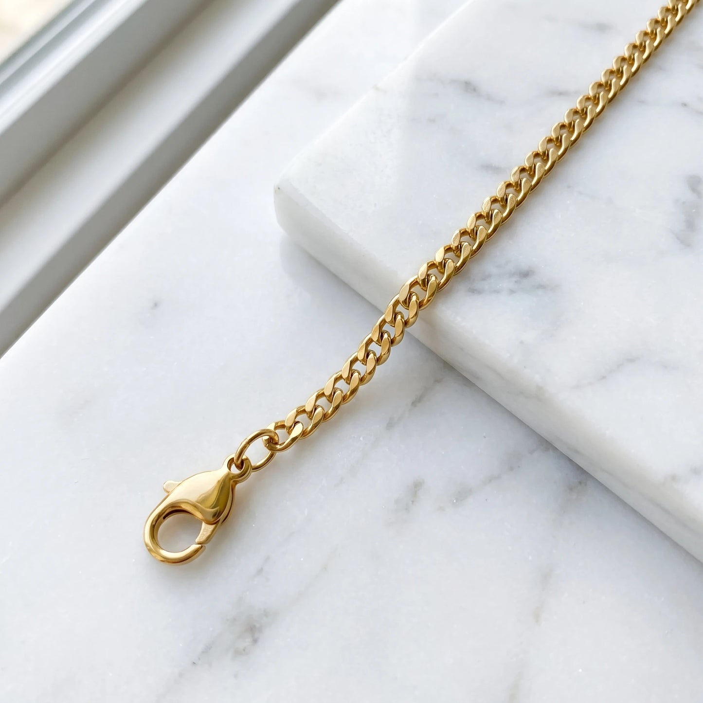 18k gold 4mm curb-link anklet macro on white marble with lobster clasp