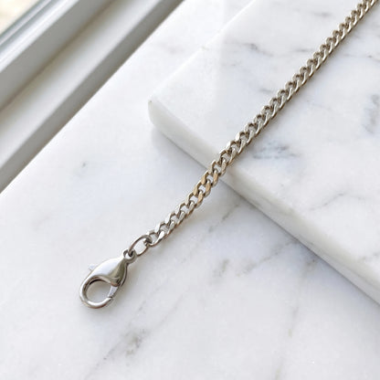 Silver 4mm curb-link anklet macro on white marble with lobster clasp