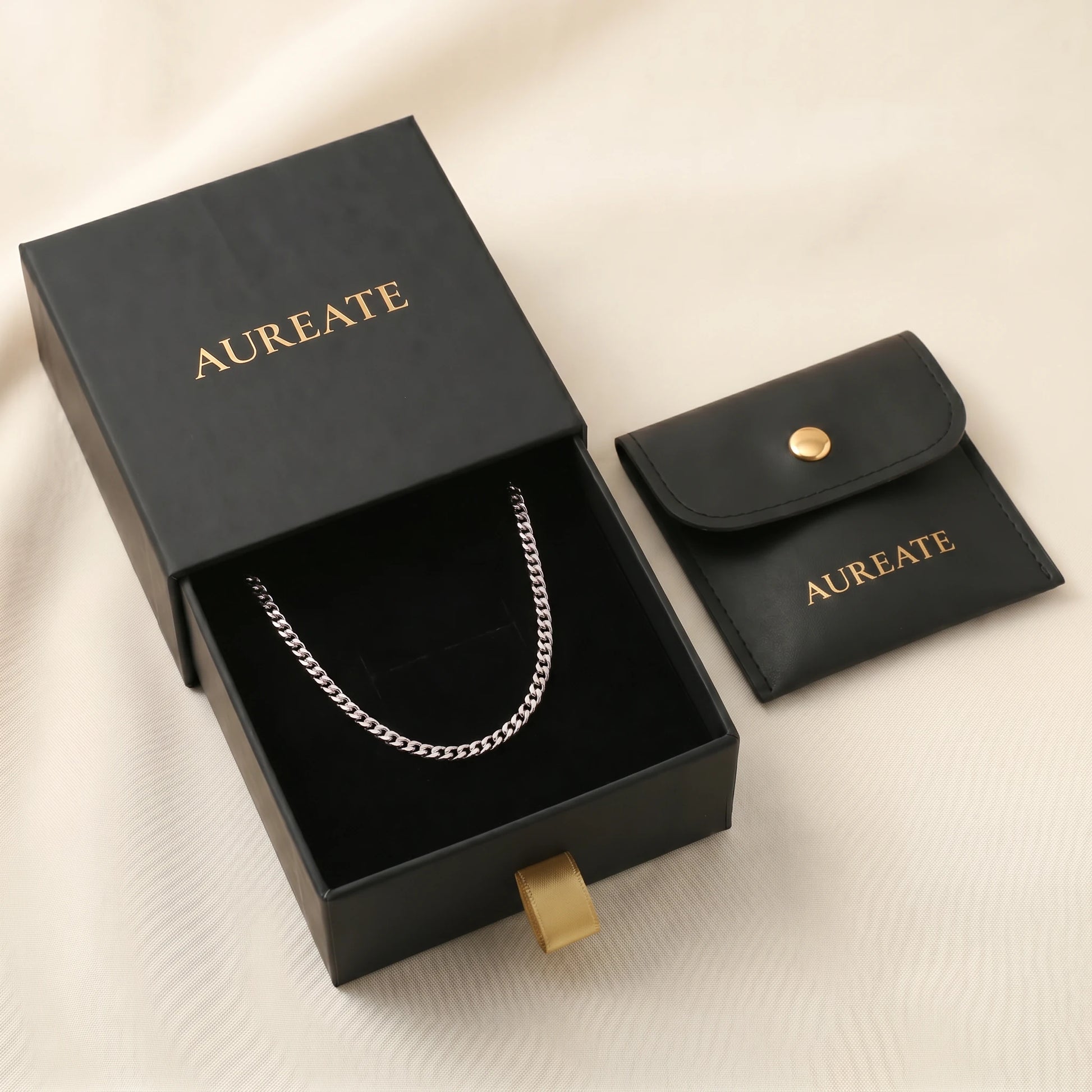 Silver 4mm curb-link anklet displayed inside open AUREATE gift box, gold logo