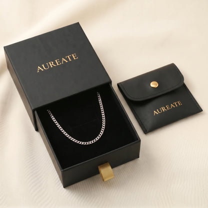 Silver 4mm curb-link anklet displayed inside open AUREATE gift box, gold logo